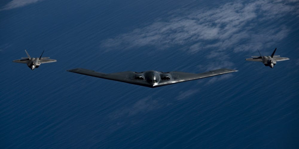 Được biết, B-2 Spirit là loại máy bay ném bom tầm xa chiến lược hiện đại nhất của Không quân Mỹ hiện nay, với thiết kế tàng hình trước radar và thiết kế khí động học độc đáo. Máy bay có thể mang theo tổng trọng lượng 18 tấn vũ khí với nhiều loại bom khác nhau, kể cả bom hạt nhân chiến thuật B61. Và ngay cả khi mang đầy đủ vũ khí, nó vẫn có tầm bay lên tới 11.000km. Ảnh: Máy bay ném bom B-2 cùng hai tiêm kích F-22 hộ tống.