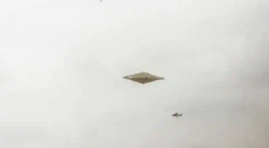 Trong ảnh, một vật thể bí ẩn hình kim cương bay trên bầu trời, phía xa là máy bay chiến đấu đuổi theo vật thể. Đây được xem là bức ảnh rõ nét nhất của UFO từng được công khai.