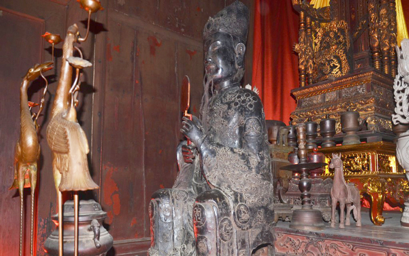 Vua đội mũ bình thiên hai cấp, trang trí "lưỡng long chầu nhật". Khuôn mặt vua vuông chữ "điền", mang phong cách của nghệ thuật tượng chân dung. Mình mặc áo long bào cổ cao, hai tay cầm hốt để trước ngực, diềm áo chảy xuống tới tận mũi hài. Thân đeo đai ngọc to bản trễ xuống, chân đi hài mũi cong.