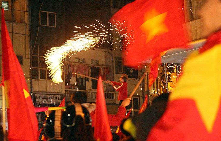 Ở phố Hàng Bông (Hà Nội), một cổ động viên đúng lên cao buộc pháo sáng vào gậy dài đốt rồi vung tung tóe khắp nơi.