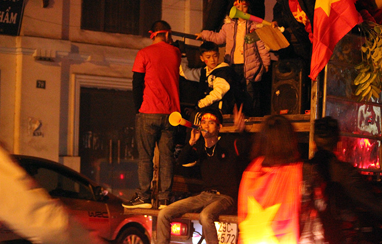Nhiều cổ động viên ngồi vắt vẻo sau xe ô tô khi di chuyển qua các tuyến đường phố Hà Nội.