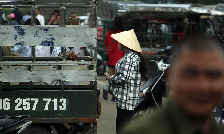 Nữ phe vé (đội nón) vừa gạ mua vé, vừa chào mời người hâm mộ mua vé. Cô chạy liên tục và gần như không nghỉ.