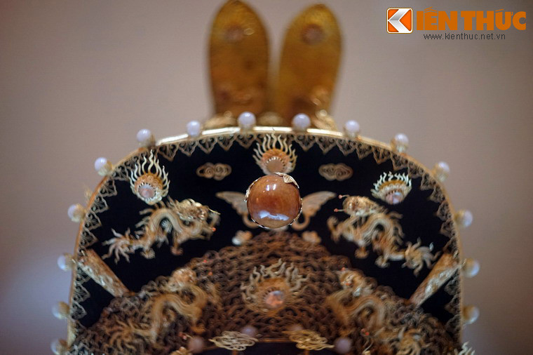 Một viên ngọc lớn màu cam được gắn ở đỉnh mũ, dường như là ngọc của loài ốc giác khổng lồ.