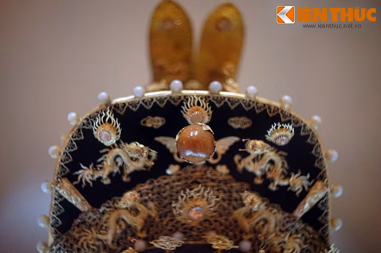 Một viên ngọc lớn màu cam được gắn ở đỉnh mũ, dường như là ngọc của loài ốc giác khổng lồ.