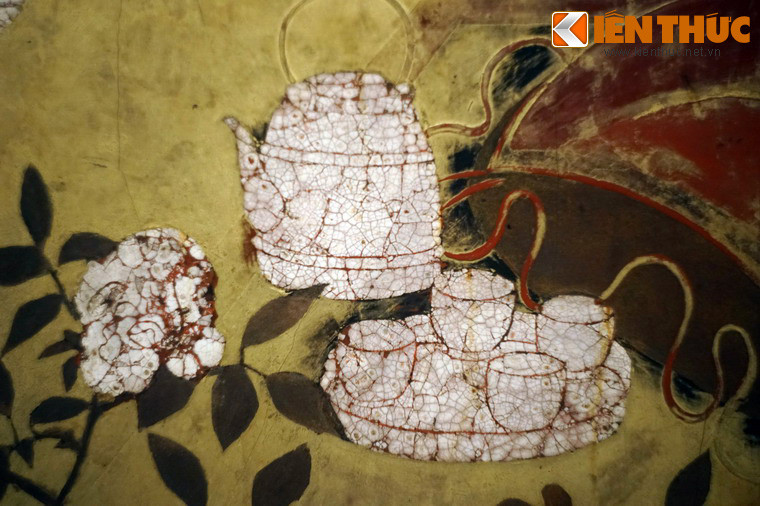 Bên một người phụ nữ có bình trà và bộ chén bốn chiếc đặt trên khay.