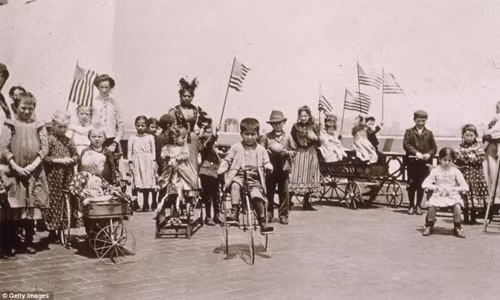 Trẻ em cầm cờ Mỹ chơi đùa trên những chiếc xe ba bánh ở thành phố New York, Mỹ thế kỷ 19.