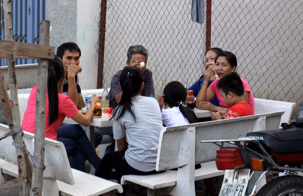 Một gia đình dựng bàn ghế đá bên trong vạch kẽ phân chia vỉa hè và ngồi ăn uống vui vẻ.