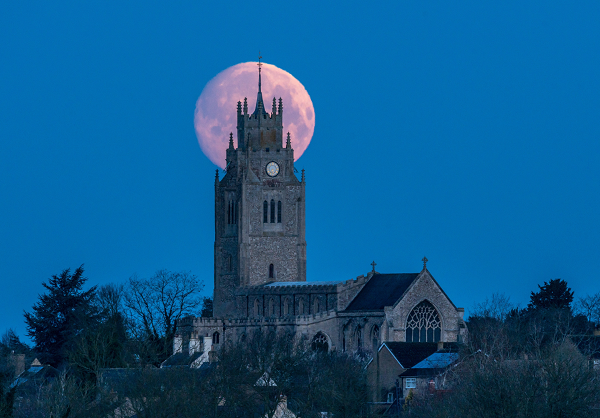 Cảnh siêu trăng được ghi lại phía sau nhà thờ St. Andrew's ở hạt Cambridgeshire, Anh vào rạng sáng 28/3.