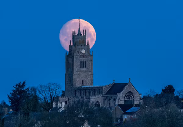 Cảnh siêu trăng được ghi lại phía sau nhà thờ St. Andrew's ở hạt Cambridgeshire, Anh vào rạng sáng 28/3.