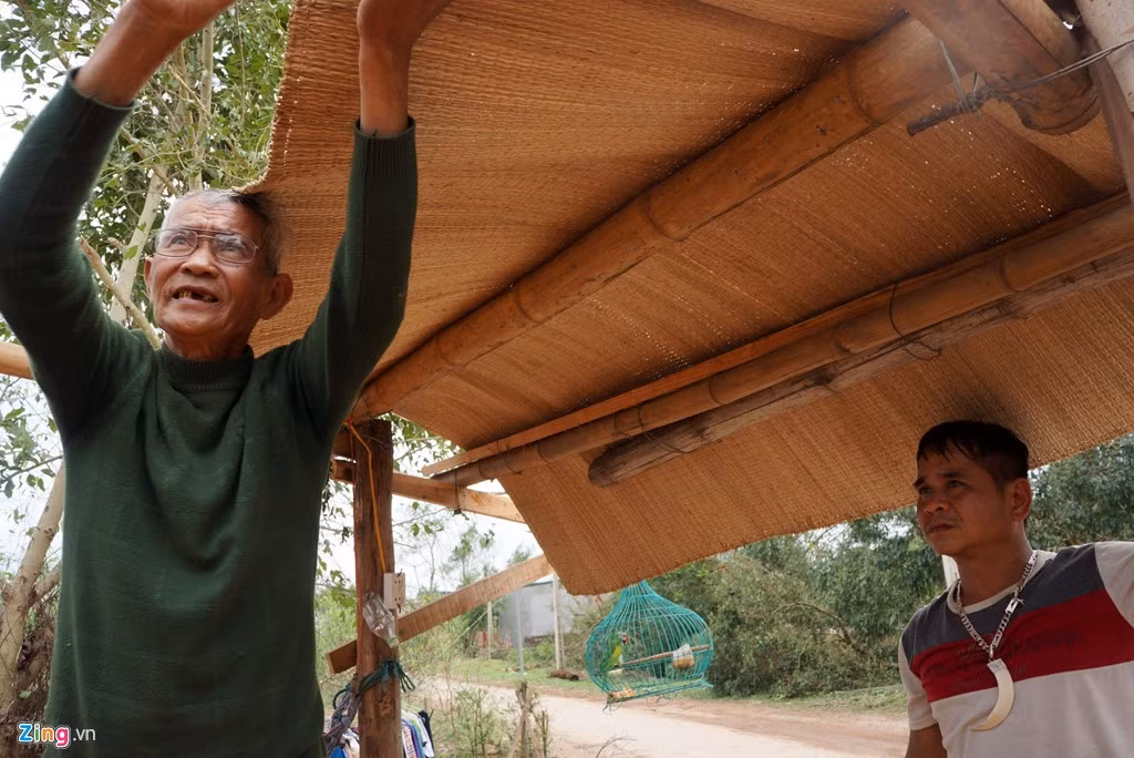 Mái nhà không còn, ông Lơn phải dùng chiếu che tạm phía trên để có chỗ ngồi sinh hoạt. Ảnh: Zingnews.