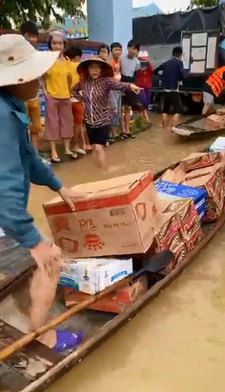 Đồ cứu trợ gồm mì tôm, nước, thuốc và các nhu yếu phẩm được đoàn của Thủy Tiên dỡ từ xe ô tô xuống ghe để đưa vào cứu trợ những người đang mắc kẹt vì lũ.