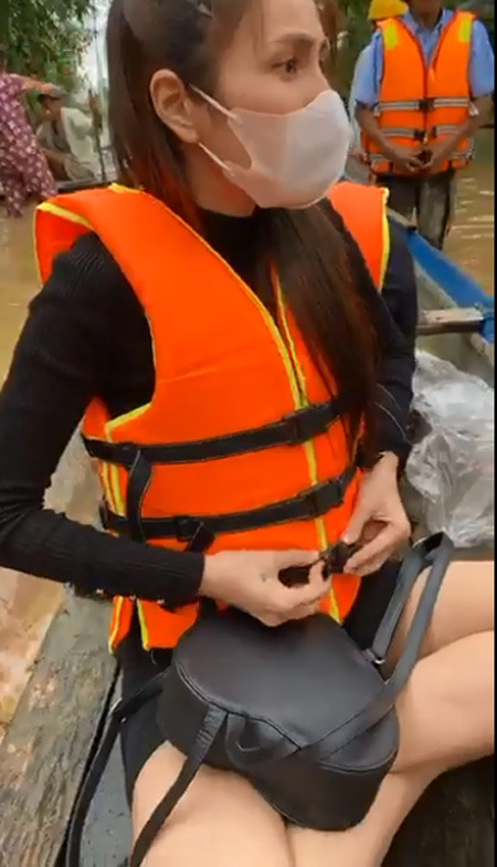 Cô mặc áo phao để chuẩn bị chèo ghe vào phát đồ cứu trợ cho những người dân bị ngập sâu quá không thể ra ngoài nhận đồ.