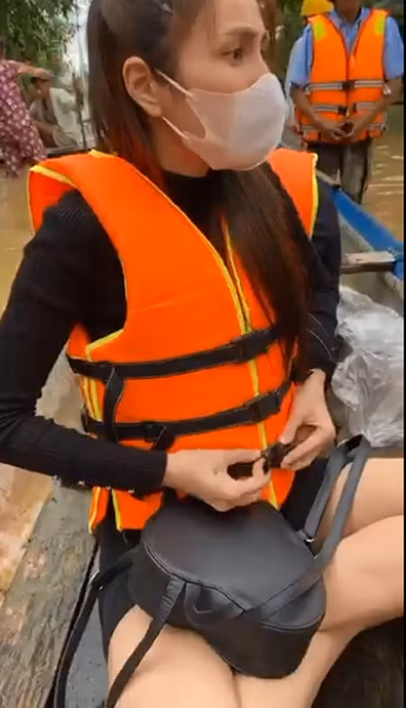 Cô mặc áo phao để chuẩn bị chèo ghe vào phát đồ cứu trợ cho những người dân bị ngập sâu quá không thể ra ngoài nhận đồ.