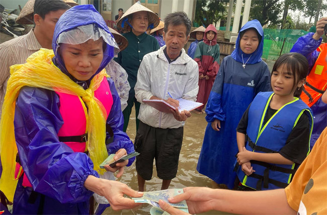 Bà lội nước, tới tận nơi trao quà cho từng người dân.