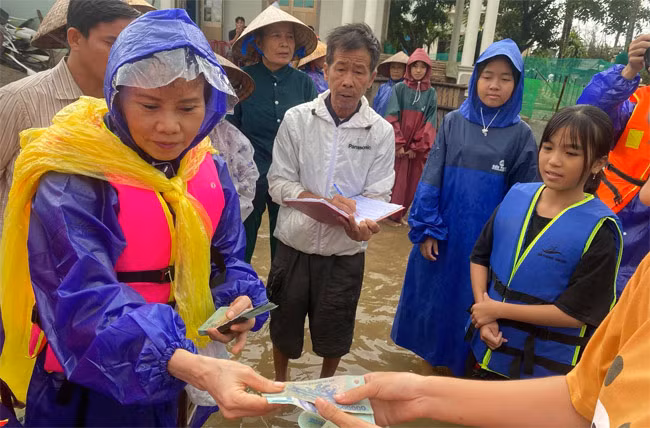 Bà lội nước, tới tận nơi trao quà cho từng người dân.