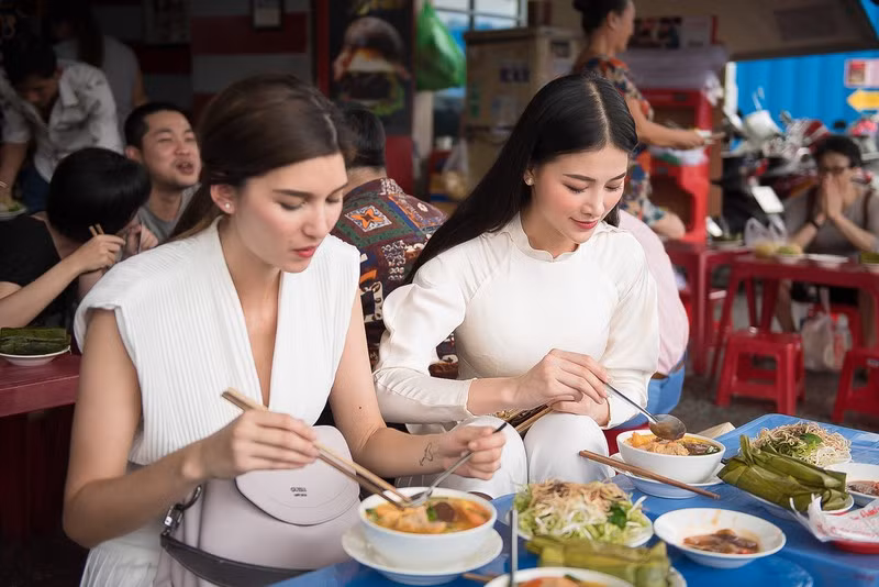 Á hậu Trái đất người Áo - Melanie Mader thích thú ngồi vỉa hè và thưởng thức món bún riêu cùng Hoa hậu Phương Khánh. Ảnh: Ngô Viết Đại Dương.