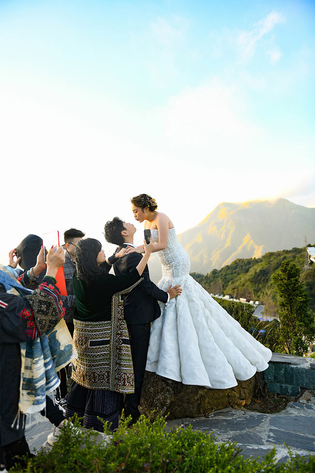 Cô dâu chú rể đang tạo dáng chụp cảnh hôn nhau.