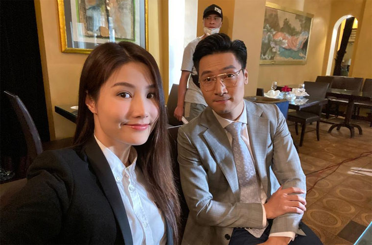 Diễm My và Mạnh Trường mặc áo vest chỉnh tề chuẩn bị cho một cảnh quay khi đóng phim giữa mùa hè.