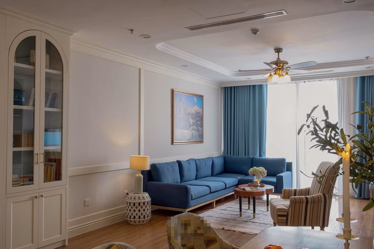 Màu xanh pastel của tủ kệ kết hợp với ghế kẻ carô xanh và lọ hoa cẩm tú cầu tô điểm cho phòng khách chút lãng mạn, trữ tình. 