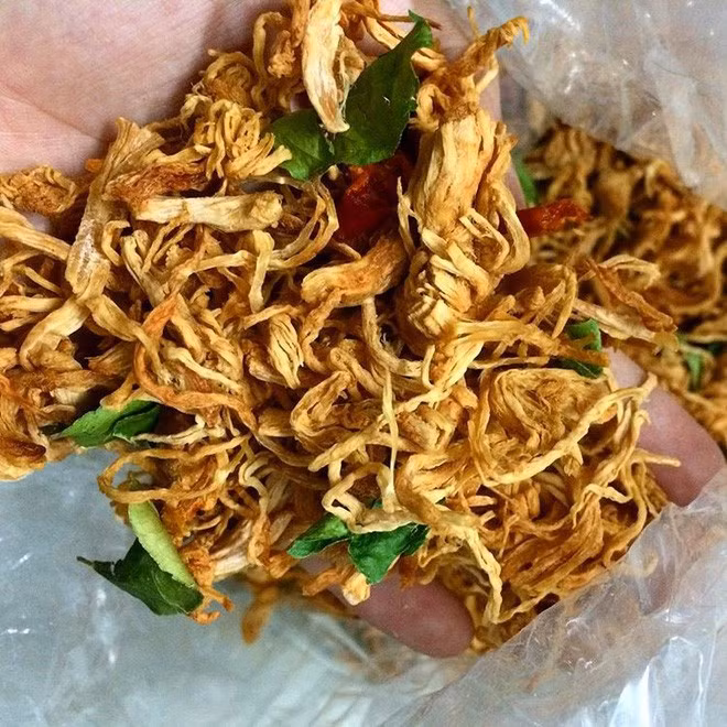 5. Khô gà lá chanh Hãy tạm quên đi món bò khô truyền thống, năm 2017, món ăn vặt đúng trend phải kể đến khô gà lá chanh cơ. Thực ra khô gà lá chanh đã bắt đầu được các shop bán đồ ăn vặt online giới thiệu từ cuối năm 2016 rồi cơ, nhưng đến 2017, món này vẫn còn nguyên độ hot. Những miếng thịt gà tẩm ướp gia vị đậm đà, xé nhỏ sấy khô khi ăn có độ ngọt của thịt, quyện với vị cay của ớt và mùi thơm của lá chanh sẽ làm đổ gục bất kỳ tín đồ ẩm thực nào. Ngoài hương vị hấp dẫn, khô gà còn ghi điểm ở chỗ thịt gà nhẹ lại xé sợi nên ăn rất dôi, 1 lạng cũng đủ nhâm nhi cả buổi. Chưa kể giá khô gà cũng rất hợp túi tiền, chỉ khoảng 30 ngàn/ lạng mà thôi.