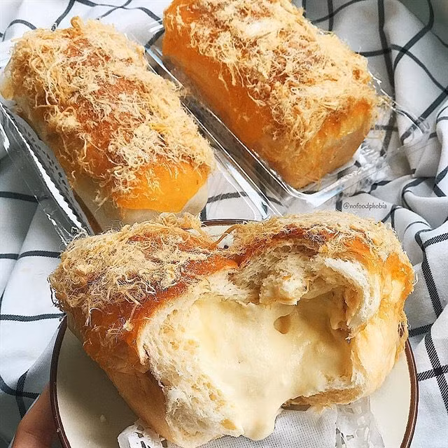 3. Bánh mì phô mai Bánh mì phô mai có lẽ là món ăn hot nhất tầm tháng 7 năm vừa qua. Ngay chỉ khi vừa xuất hiện ở vài tiệm bánh online, món bánh này đã kịp 'hô mưa gọi gió' bởi sự độc đáo của nó. Điểm độc đáo nhất của bánh mì phô mai là ở giữa mỗi ổ bánh đều chứa đầy nhân phô mai. Khi bẻ bánh, bạn sẽ thấy lớp phô mai thơm nức, sóng sánh chảy ra vô cùng ngon mắt.