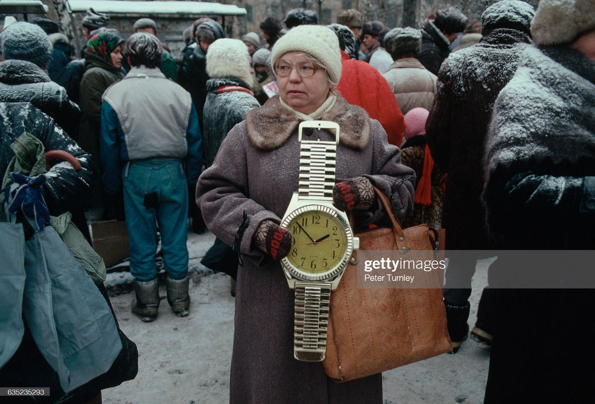 Một cụ bà cố gắng bán chiếc đồng hồ treo tường có hình dáng giống chiếc đồng hồ đeo tay khổng lồ trên con phố đông đúc tuyết phủ ở Moscow, cuối năm 1991, khi sự tồn tại của Liên Xô chỉ còn tính bằng ngày.