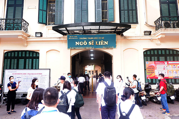 Trước khi đo thân nhiệt học sinh phải xếp hàng để được xịt khử khuẩn. 