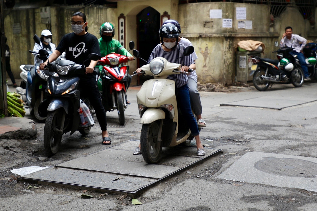 Xe máy của người phụ nữ này bị mắc kẹt bởi nắp cống nhô quá cao.