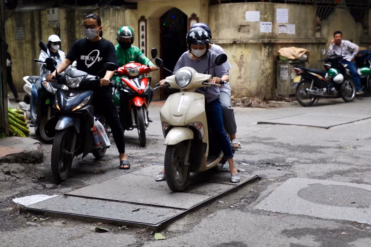 Xe máy của người phụ nữ này bị mắc kẹt bởi nắp cống nhô quá cao.