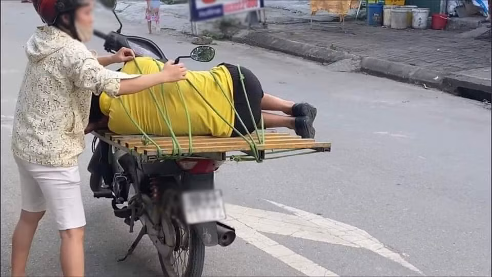 Mạng xã hội đã chia sẻ bức ảnh ghi lại cảnh người phụ nữ đặt chồng lên yên sau xe máy sau đó dùng dây buộc lại thật chặt. Trong khi vợ thoăn thoắt dùng dây buộc chồng lại phía sau thì anh ta chỉ biết nằm co ro, say mèm. Trước lúc đi, người phụ nữ còn kiểm tra lại một lượt để xem liệu có chắc chắn và đảm bảo chồng an toàn.