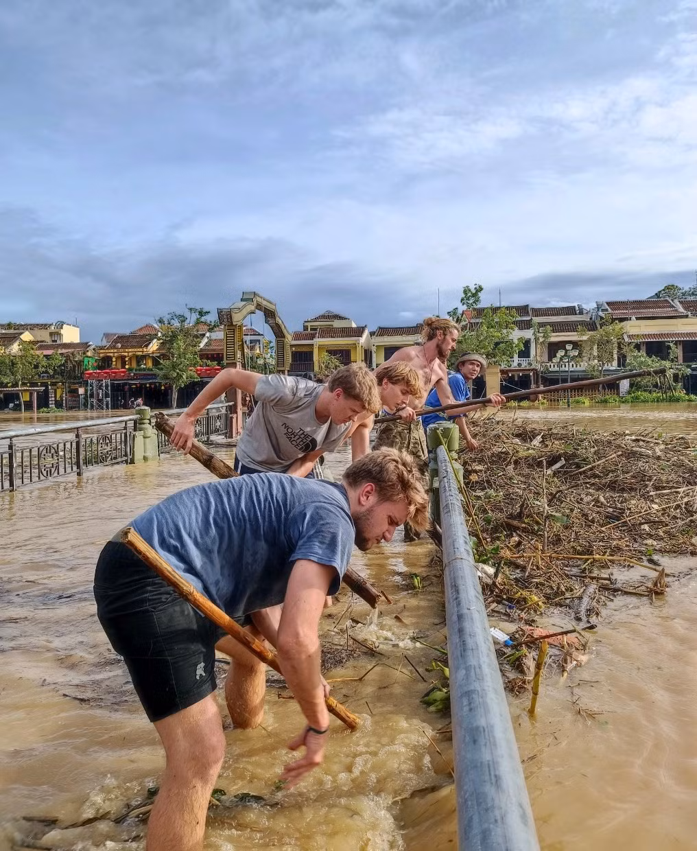 Trong số đó hình ảnh một nhóm du khách nước ngoài hì hục dọn rác, khai thông dòng lũ đang chảy qua một cây cầu bắc ngang sông Hoài đã làm cư dân mạng ấm lòng. Ảnh: Afamily