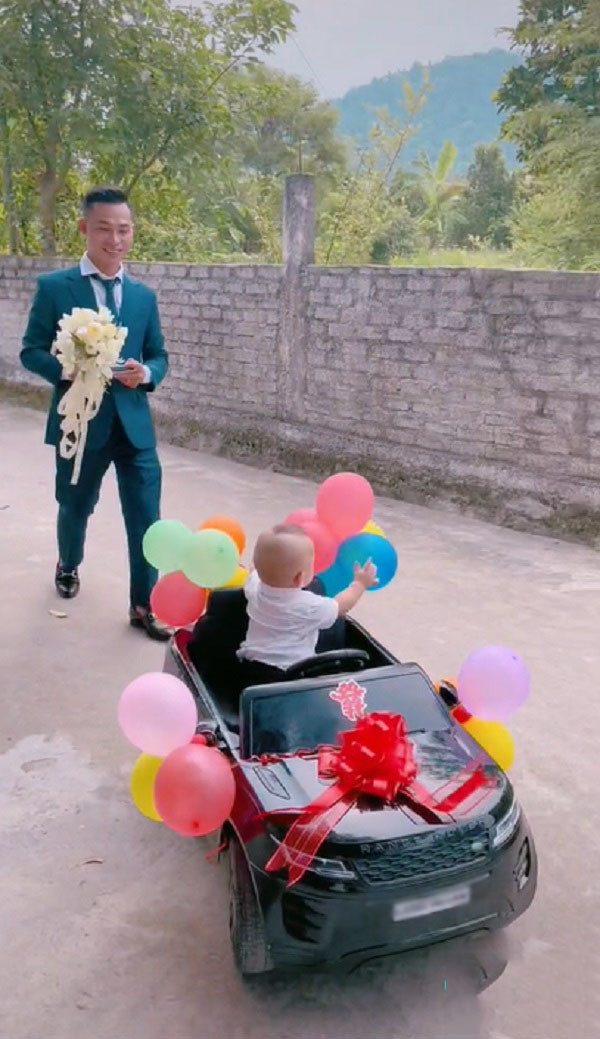 Xem clip có thể thấy, con trai của cô dâu chú rể được bố mẹ chuẩn bị cho rất chỉn chu, mặc áo sơ mi trắng, cổ thắt nơ. Cậu bé hồn nhiên điều khiển chiếc xe ô tô, thỉnh thoảng ngoái đầu lại nhìn bố vô cùng thích thú.