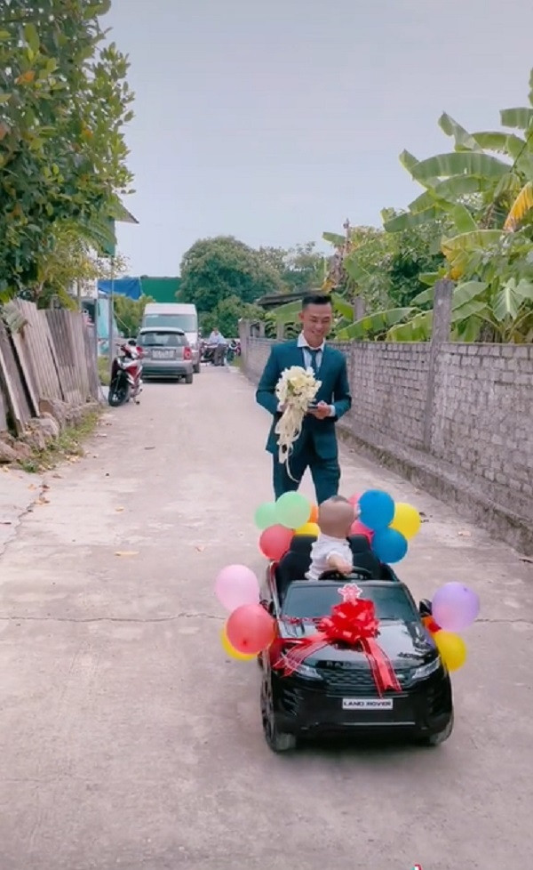 Cậu bé ngồi trên chiếc xe ô tô đồ chơi được dán chữ hỷ và trang trí bóng bay dẫn đường cho bố đi “rước mẹ về dinh” khiến nhiều người bật cười.