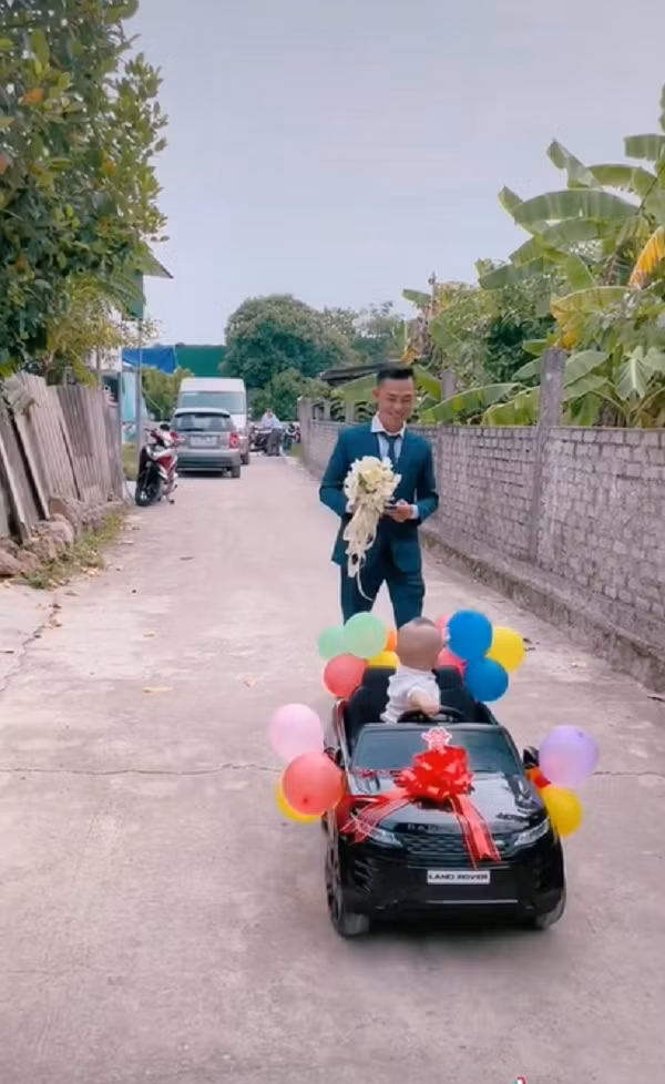 Cậu bé ngồi trên chiếc xe ô tô đồ chơi được dán chữ hỷ và trang trí bóng bay dẫn đường cho bố đi “rước mẹ về dinh” khiến nhiều người bật cười.