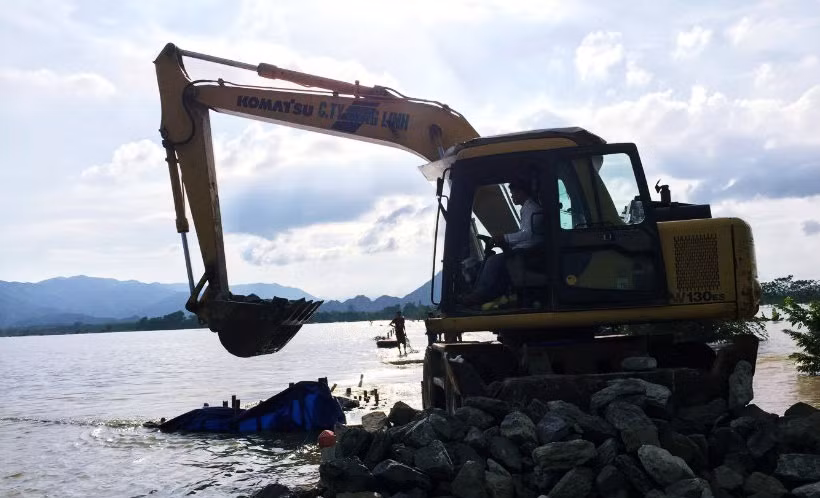 Các máy xúc đổ đá để nối lại đoạn đê bị vỡ, ngăn không cho nước chảy tràn vào khu vực người dân địa phương sinh sống.