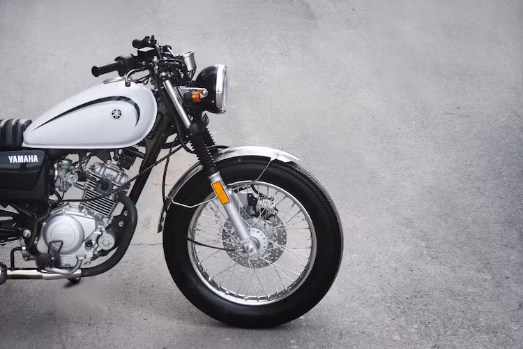 Với gói độ này, chiếc YB125SP sẽ có kiểu dáng của một mẫu xe môtô cổ điển, tương tự các dòng xe nổi tiếng như Honda CB750 hay Triumph Bonneville, trong khi vẫn giữ nguyên phần lớn các chi tiết nguyên bản. Bắt đầu từ bánh xe, cặp vành đúc 5 cây của YB125SP đã bị loại bỏ, thay vào đó là bánh căm kèm lốp vân zig zag phong cách Firestone cổ điển.