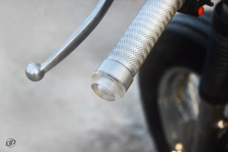Một trong những thế mạnh của DuongDoan Design là tiện CNC, chính vì vậy bản độ GN125 cafe racer này cũng xuất hiện khá nhiều chi tiết kim loại gia công thủ công như ốc chảng ba hay bao tay. Đặc biệt, 2 bên gù tay lái được tích hợp xi-nhan do xưởng tự tạo ra, tương tự loại xi-nhan của hãng Motogadget nổi tiếng.