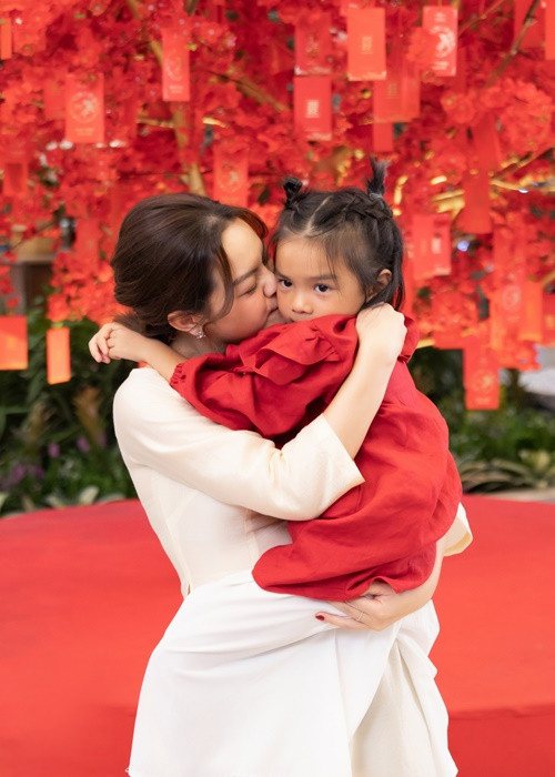 Bé Tuệ An diện áo dài đỏ, búi tóc tinh nghịch.