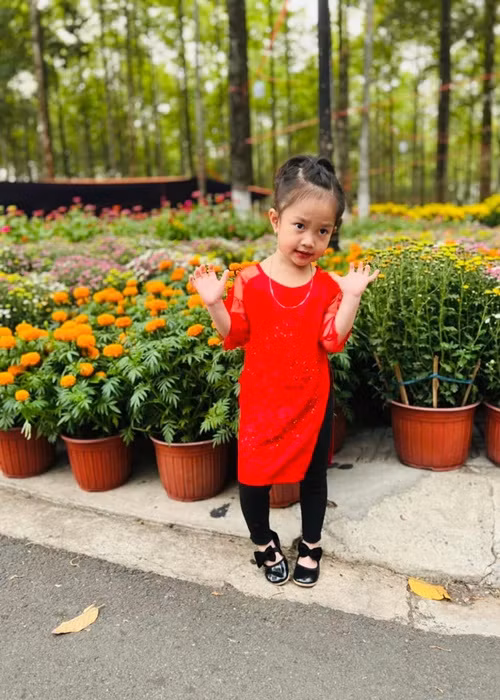 Bảo Nhi - con gái của Lê Dương Bảo Lâm diện áo dài đỏ đi chợ hoa. Ảnh: Yan