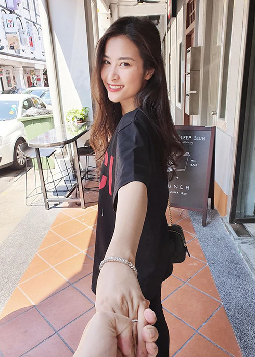 Đôi vợ chồng son mặc đồ đôi, nắm lấy tay nhau chụp ảnh.