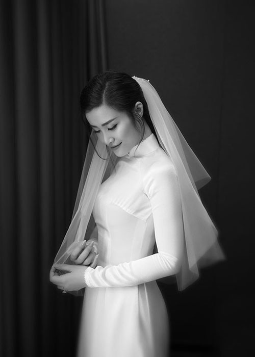 Trước đó, trong lễ ăn hỏi, Đông Nhi mặc chiếc áo dài trắng. Thiết kế chuẩn form dáng cổ điển thập niên 60 tôn lên vòng eo con kiến của người mặc.