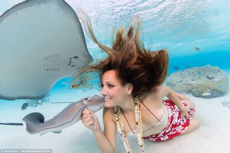 Người mẫu xinh đẹp cười đùa cùng với những con cá đuối.