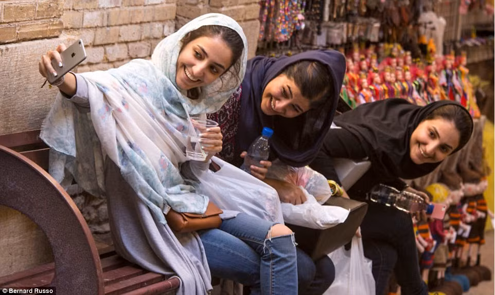 Ba người phụ nữ chụp ảnh “tự sướng” cạnh quầy bán đồ chơi tại một khu chợ ở thành phố Shiraz.