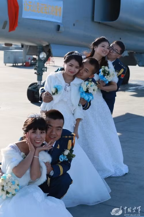 Các cặp đôi chụp ảnh trước một máy bay chiến đấu.