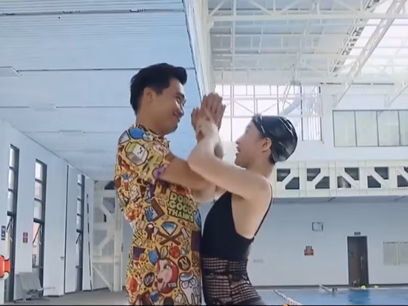 Trong buổi học bơi tiếp theo, Bách giả vờ bị đuối nước khiến cô giáo dạy bơi lao xuống cứu. "Từ ngày hôm nay tôi quyết định sẽ cách chức cô giáo, thăng chức cô giáo lên chức mới - chức người yêu anh", Bách tỏ tình. Ảnh: VTV