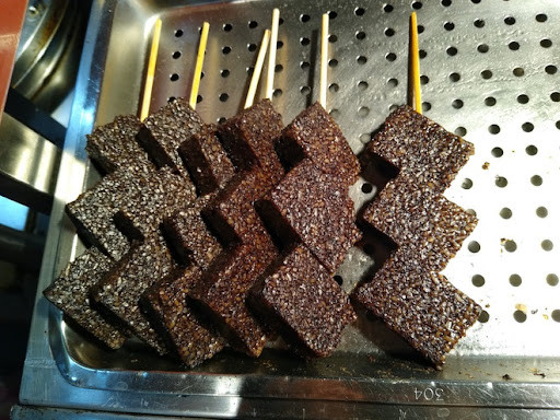 Món bánh được làm từ gạo nếp cùng tiết heo, phủ đậu phộng bên ngoài và rau mùi. 