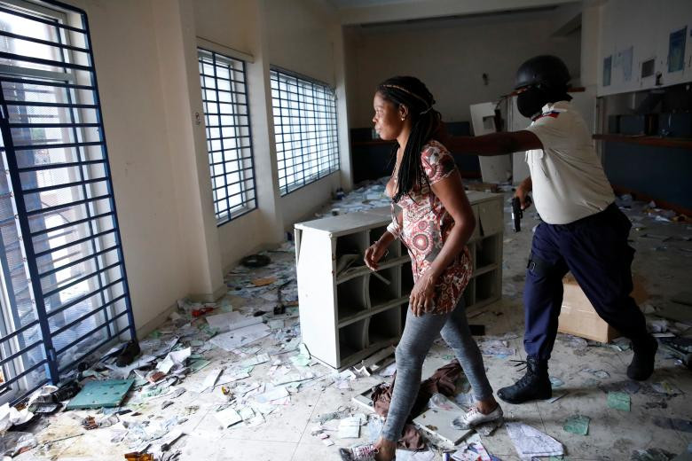 Cảnh sát Haiti áp giải một phụ nữ được tìm thấy trong một ngân hàng bị cướp phá ở Port-au-Prince.