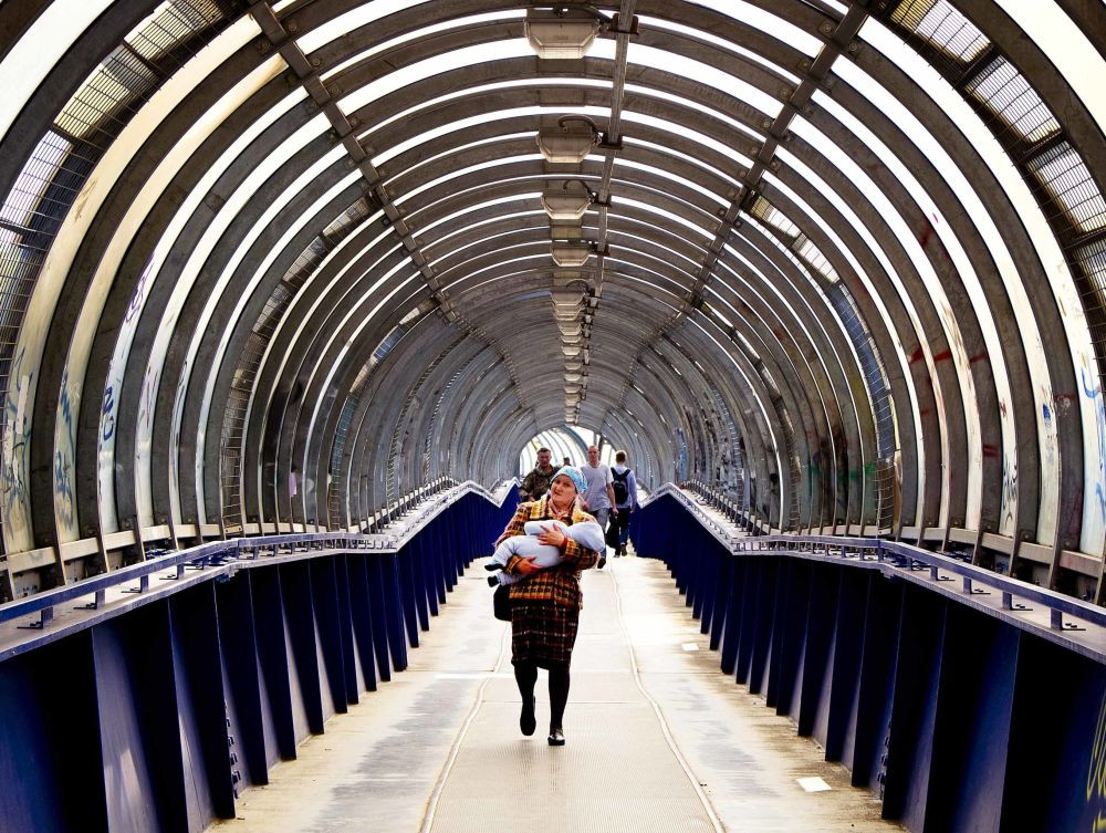 Một phụ nữ bế con đi qua cây cầu đi bộ ở Podolsk gần thủ đô Moscow ngày 19/6.