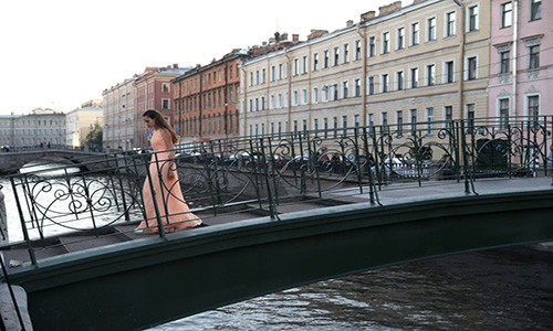 Người phụ nữ đi qua cây cầu ở thành phố St.Petersburg hôm 25/6.