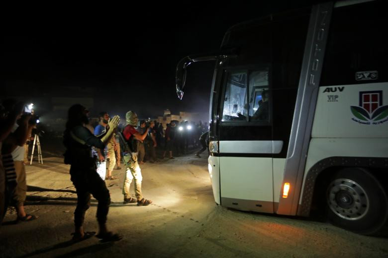 Các tay súng HTS đứng gần một chiếc xe buýt chuẩn bị rời khỏi ngôi làng al-Foua và Kefraya.